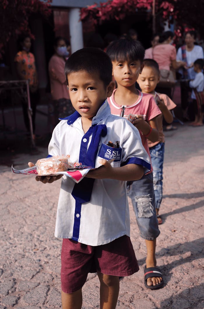 Young boys lined up outdoors in Mandalay to receive donations during a charity event.