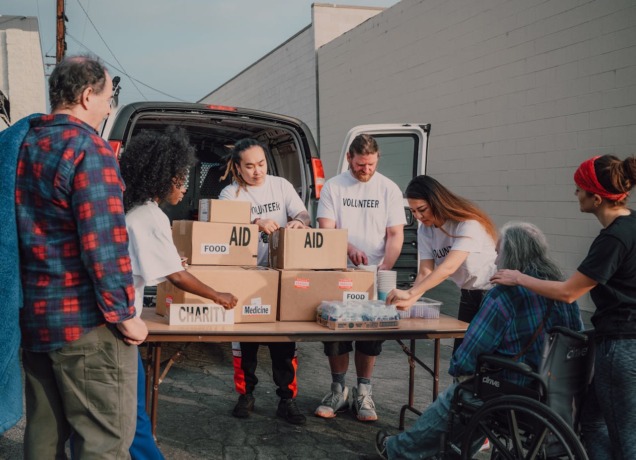 gallery-5 Group of diverse volunteers organizing aid packages outdoors for a charity event.
