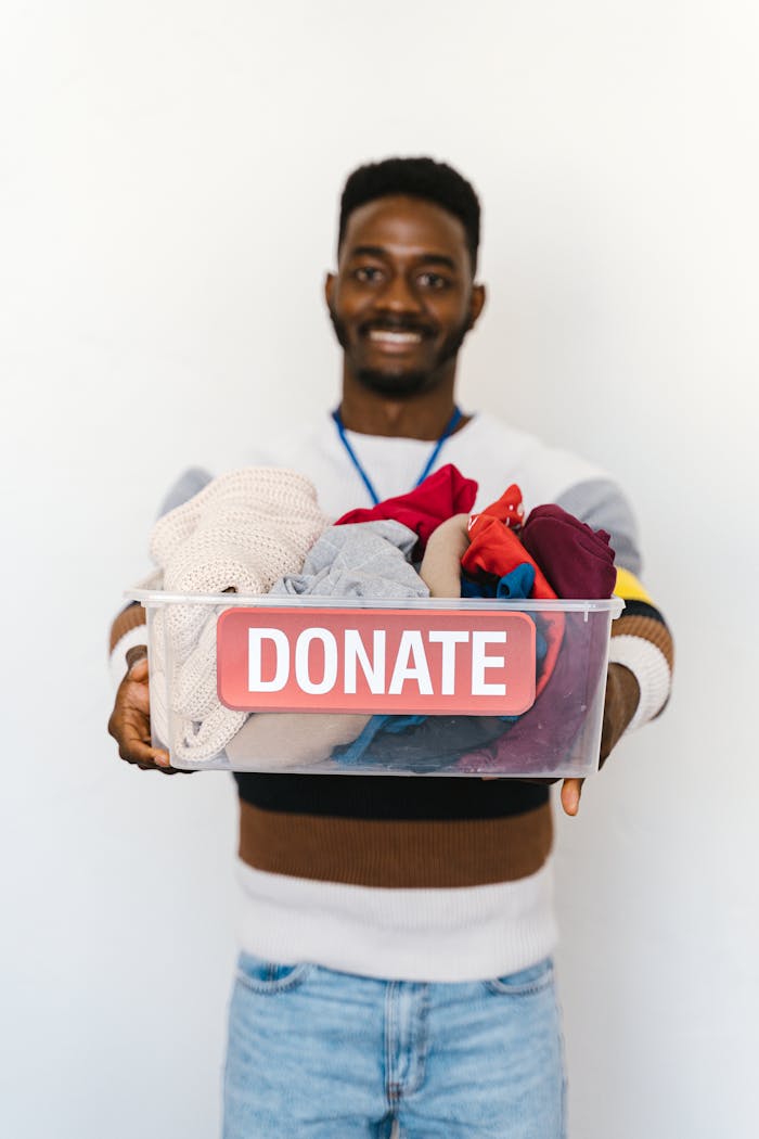 services-01 A cheerful volunteer holds a donation box filled with clothes, encouraging charitable giving.